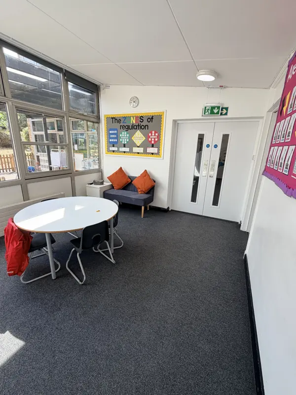 Small school room with a round table, sofa and clean carpet