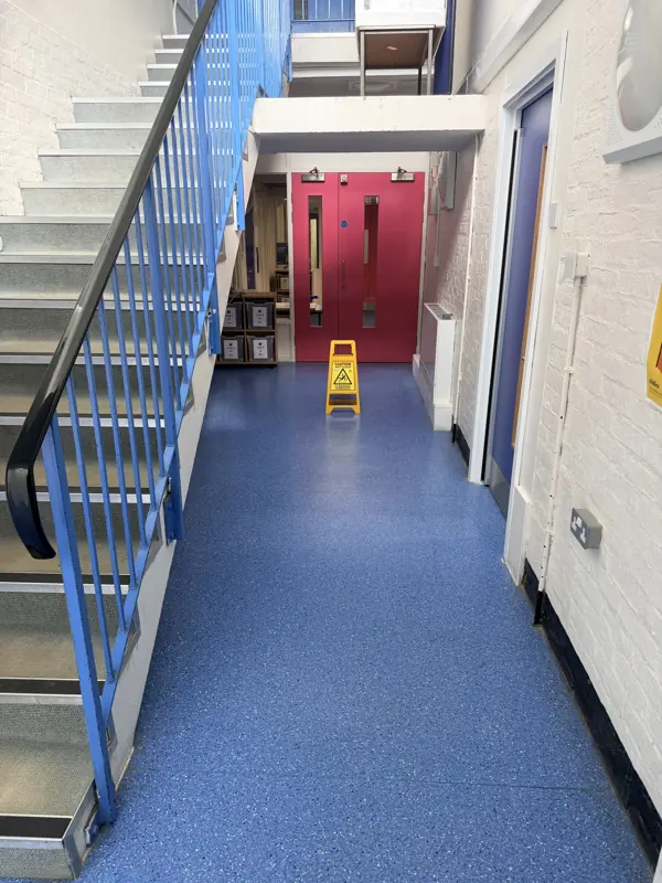 School stairwell with blue railings and a cleaned blue floor