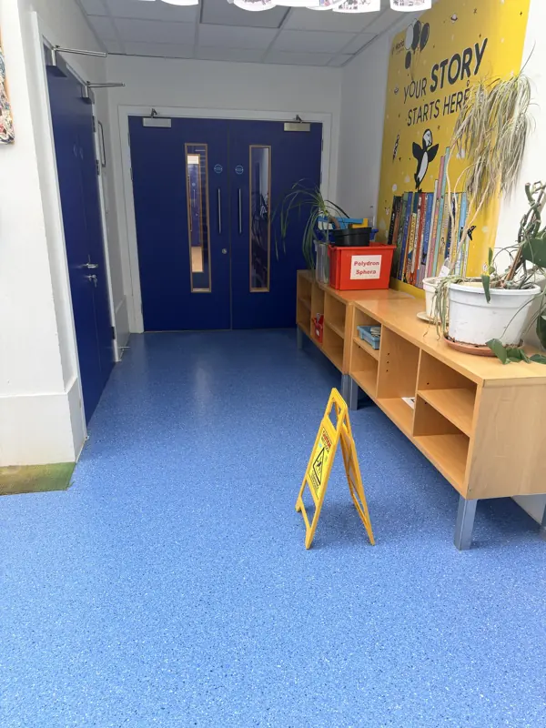 Blue vinyl school corridor with a wet floor sign
