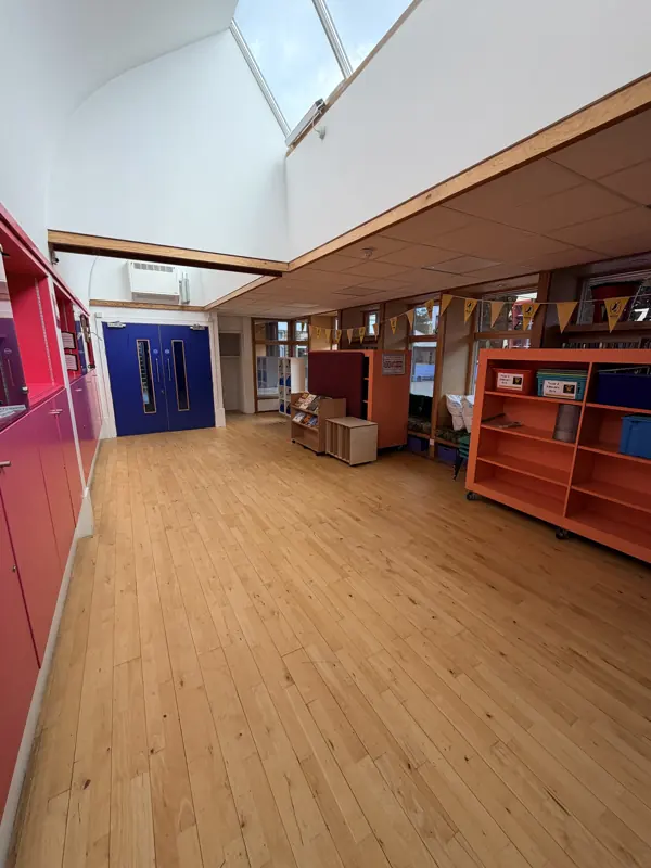School library with a polished wooden floor and bright orange shelving