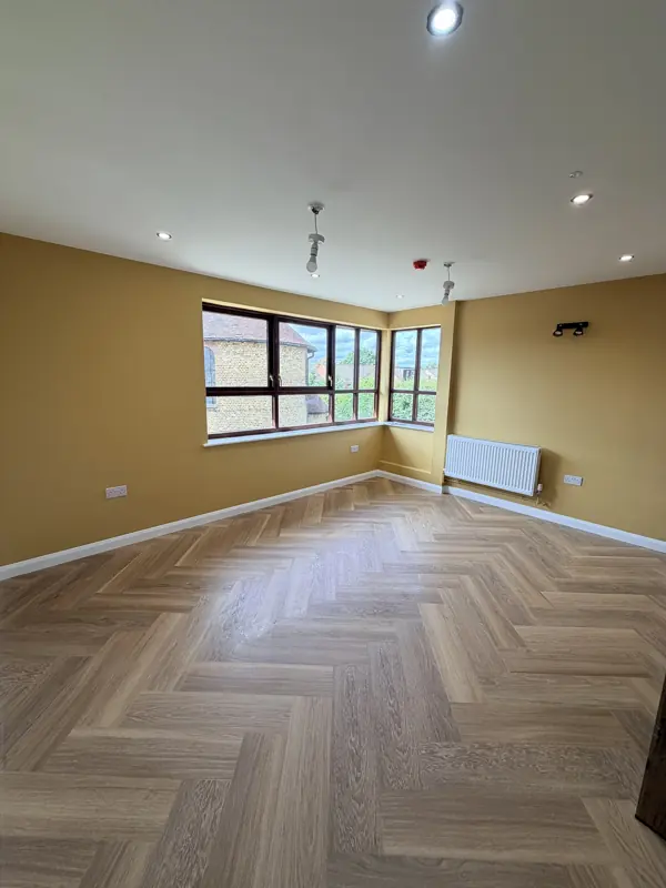 Empty room with mustard walls and a freshly cleaned herringbone floor