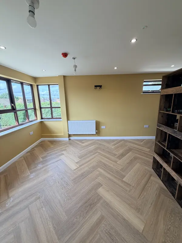 Mustard-walled room with herringbone floor and bookcase